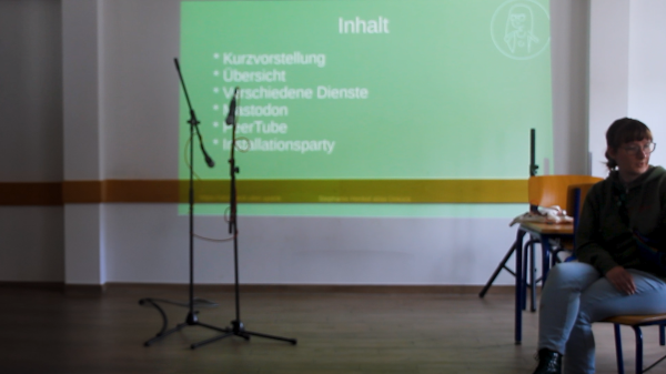 Aufnahme von mir an einem Tisch mit einer Präsentation im Hintergrund Screenshot%20Workshop